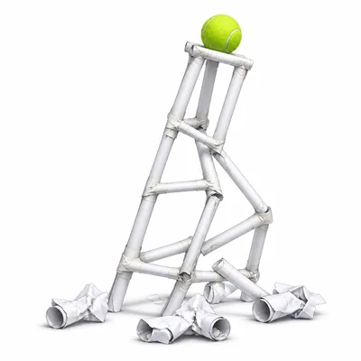 A paper tower prototype collapsing under a tennis ball.